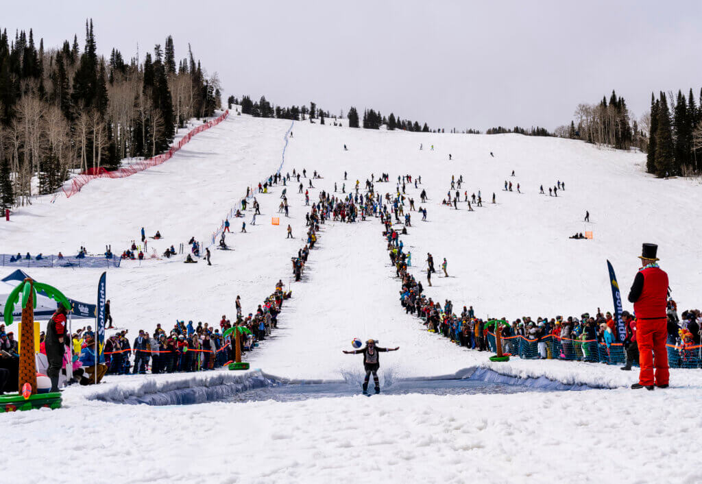 Skiers and snowboarders watching and participating in Solitude's Pond Skim Beach Party during the spring